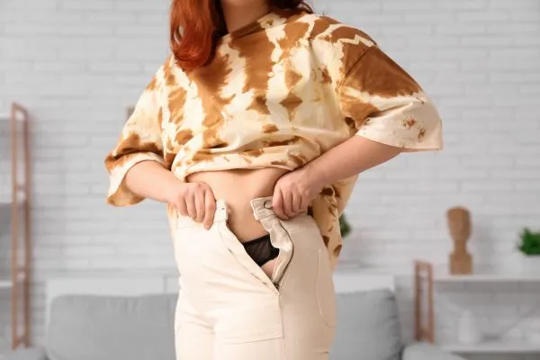 Image of woman trying to do her trousers up after pregnancy weight gain Malvern Link