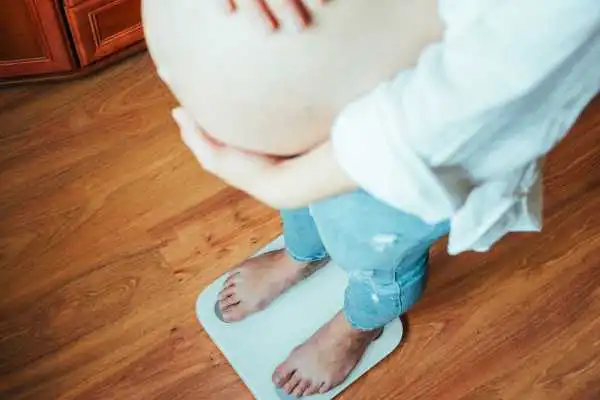 Image of woman weighing herself and experiencing weight gain through pregnancy Malvern Link